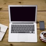 Laptop met notitieboekje en kopje koffie